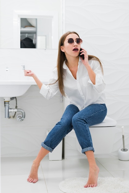 Zdjęcie kobieta rozmawia przez telefon, siedząc w toalecie