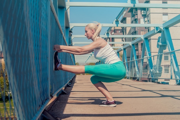 Kobieta runner rozciąganie nogi przed uruchomieniem. Piękna młoda kobieta atlety pracy. Koncepcja fitness