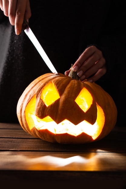 Kobieta rzeźbi dynię na Halloween