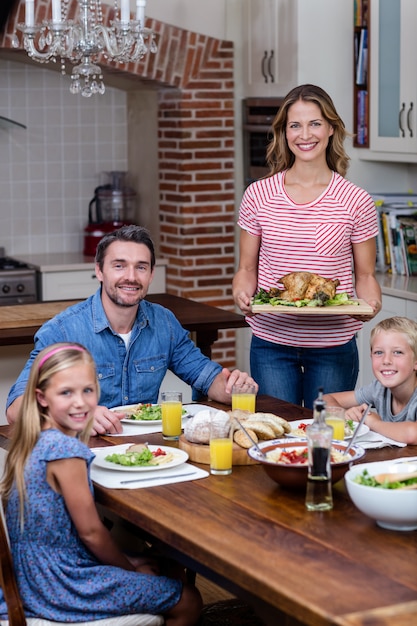 Zdjęcie kobieta serwująca jedzenie do swojej rodziny w kuchni