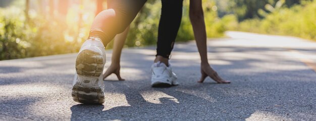 Kobieta siedząca i przygotowująca się do joggingu, biega w parku, do którego rano i wieczorem przychodzi wiele osób, bieganie jest popularnym zajęciem. Koncepcja opieki zdrowotnej z joggingiem