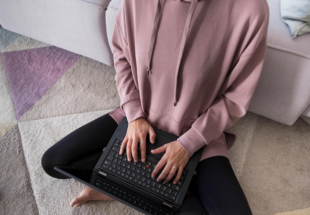 Kobieta siedząca na dywanie pracująca z laptopem