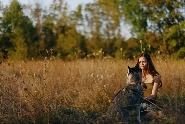 Kobieta siedząca na polu z psem jamnikiem uśmiechająca się podczas spędzania czasu na świeżym powietrzu z psim przyjacielem