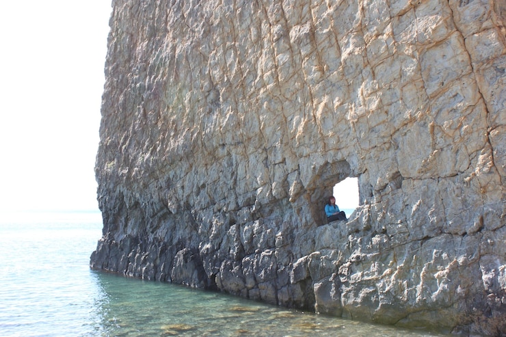 Zdjęcie kobieta siedząca na skałach na plaży