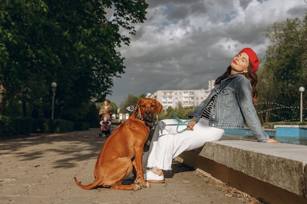 Kobieta Siedząca Przy Fontannie Z Psem Rasy Rhodesian Ridgeback W Parku