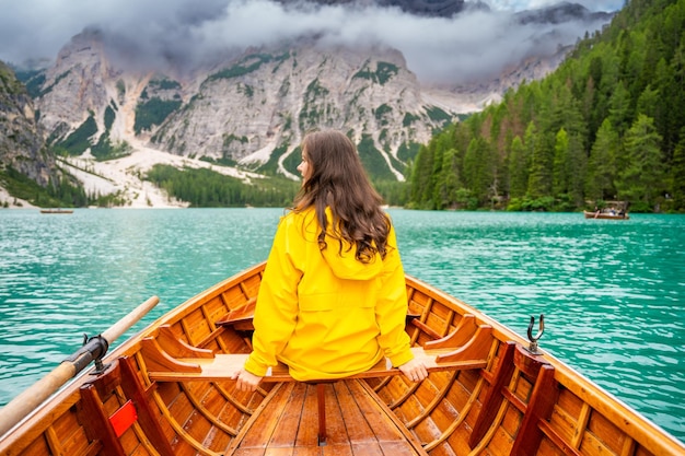 Kobieta siedząca w dużej brązowej łodzi na jeziorze Lago Braies w pochmurny dzień Włochy Letnie wakacje w Europie