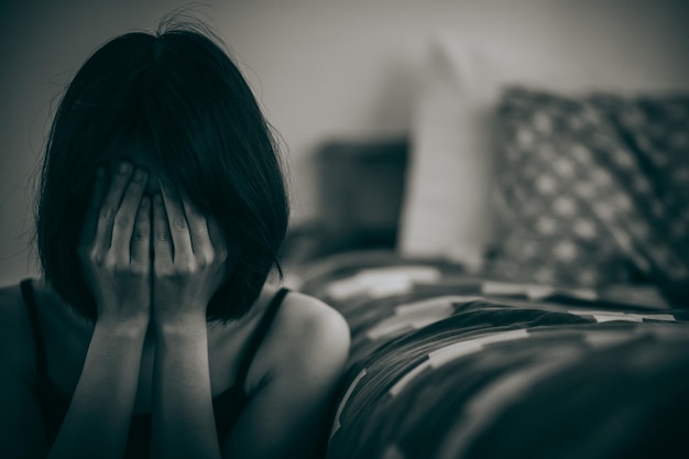 Kobieta siedząca z rękami zakrywającymi twarz w żałobie po rozczarowaniu życiem