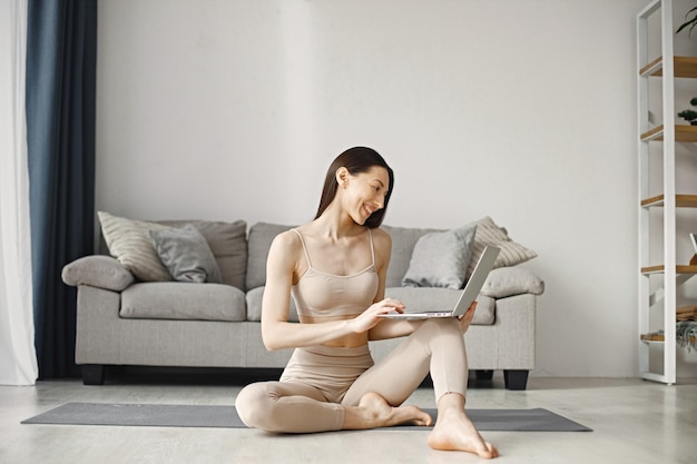 Kobieta siedzi na jogi mężczyzna w legginsach i górze podczas korzystania z laptopa w domu