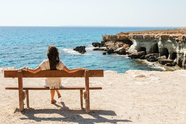 Kobieta siedzi na ławce w pobliżu klifów morskich w punkcie widokowym Cape Greco, ciesząc się scenerią i naturalnym pięknem