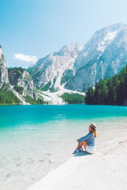 Kobieta siedzi na plaży górskiego jeziora w sezonie letnim widok na malowniczy krajobraz