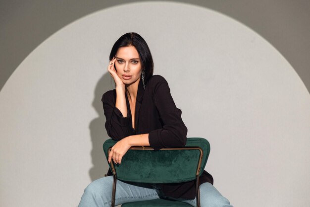Kobieta siedzi na zielonym krześle przed okrągłą białą ścianą.