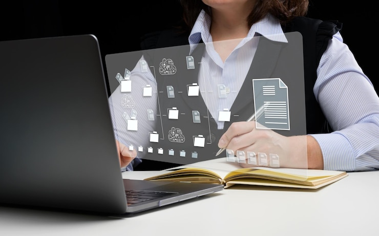 Zdjęcie kobieta siedzi przy stole i pracuje z laptopem mystem zarządzanie dokumentami oprogramowanie dms do automatyzacji archiwizacji i efektywnego zarządzania plikami informacyjnymi