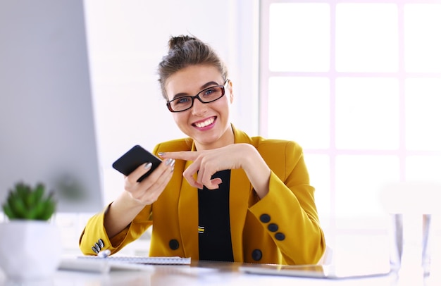 Kobieta siedzi w biurze z laptopem na telefonie