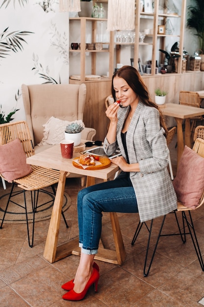 Kobieta siedzi w kawiarni i je truskawki. Dziewczyna z truskawkami w dłoniach w kawiarni.