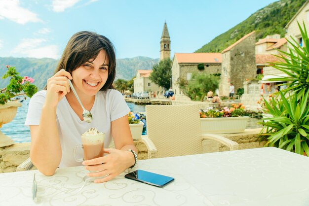 Kobieta siedzi w kawiarni nad brzegiem morza w Czarnogórze jedząc lody