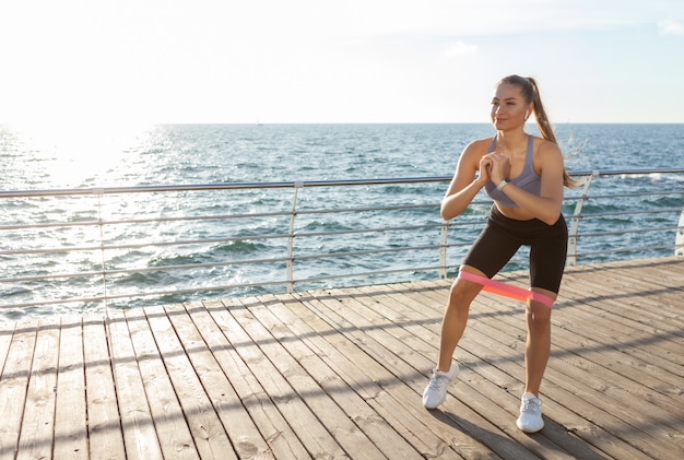 Kobieta Slim Fit W ćwiczeniach Sportowych Z Gumkami Fitness Na Plaży O Wschodzie Słońca