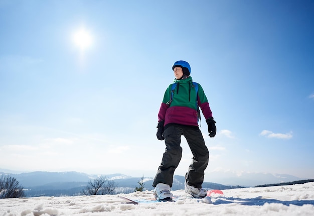 Kobieta snowboardzistka na tle przestrzeni kopii błękitnego nieba i ośnieżonych gór Koncepcja sportów ekstremalnych