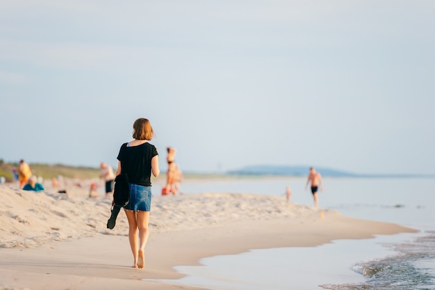 Kobieta spaceru wzdłuż plaży w lecie.