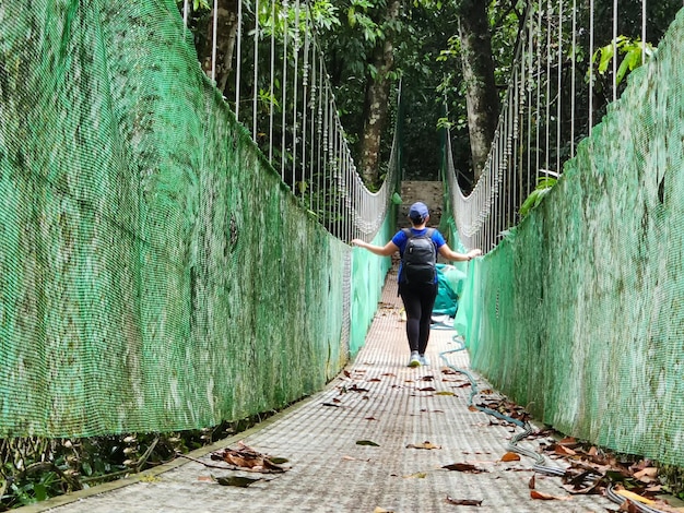 Kobieta spacerująca po wiszącym moście w dżungli Tabin w Lahad Datu Sabah, Malezja