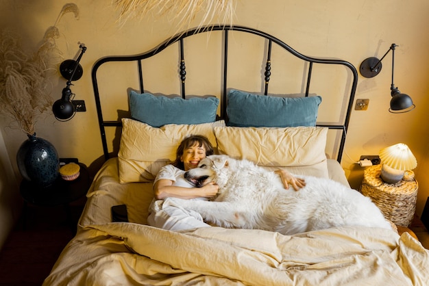 Zdjęcie kobieta śpi ze swoim ogromnym i uroczym psem w łóżku