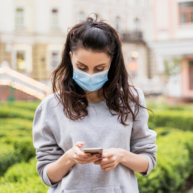 Kobieta sprawdza jego telefon mając na sobie maskę