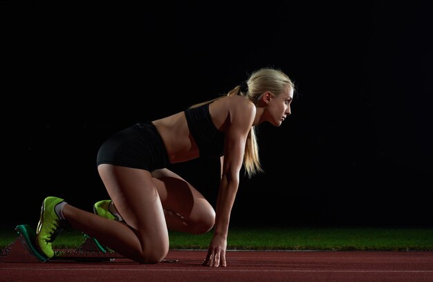 kobieta sprinter pozostawiając bloki startowe na torze lekkoatletycznym. Widok z boku. wybuchający początek