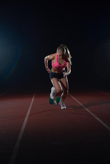 kobieta sprinter pozostawiając bloki startowe na torze lekkoatletycznym. Widok z boku. wybuchający początek