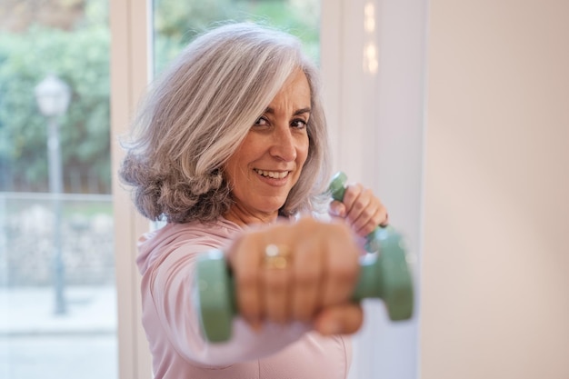 Kobieta starsza uprawiająca sport w domu, aby zachować zdrowie Koncepcja sportu w opiece zdrowotnej dla osób starszych ćwiczenia fizyczne