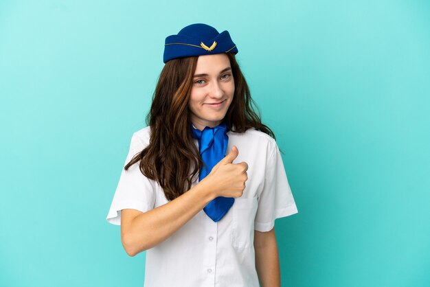 Kobieta stewardesa samolotu na białym tle na niebieskim tle dająca gest kciuka w górę