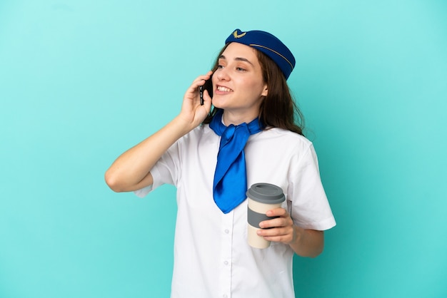 Kobieta Stewardesa Samolotu Na Białym Tle Na Niebieskim Tle Trzymająca Kawę Na Wynos I Telefon Komórkowy
