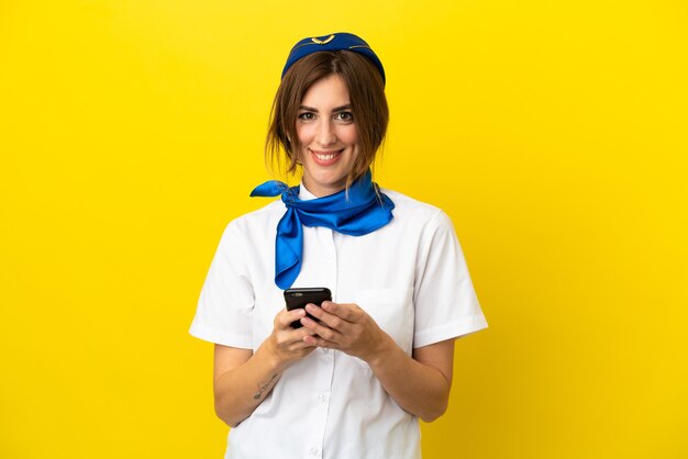 Kobieta Stewardesa Samolotu Na Białym Tle Na żółtym Tle Wysyłająca Wiadomość Za Pomocą Telefonu Komórkowego
