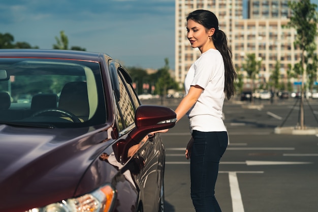 Kobieta stoi obok nowego samochodu na parkingu