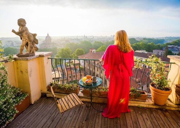 Zdjęcie kobieta stojąca na balkonie i z widokiem na miasto rano