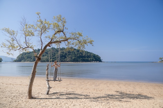 Kobieta stojąca na huśtawce na plaży.