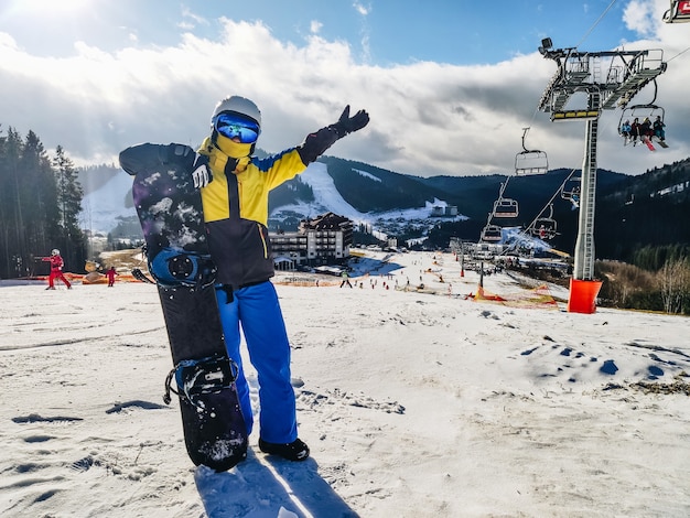 Kobieta stojąca na wzgórzu ośrodka narciarskiego z zimowymi zajęciami na snowboardzie