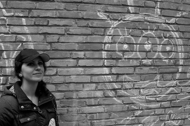 Kobieta stojąca przeciwko graffiti na ceglanej ścianie