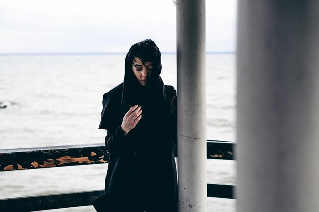 Zdjęcie kobieta stojąca przy balustradzie przeciwko morzu