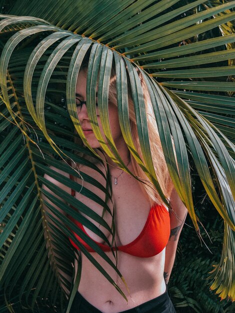 Zdjęcie kobieta stojąca przy liściach palmowych