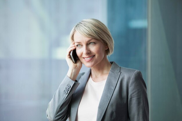 Kobieta stojąca przy oknie za pomocą telefonu komórkowego