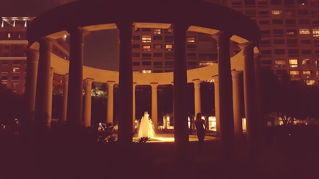Kobieta stojąca przy oświetlonej fontannie
