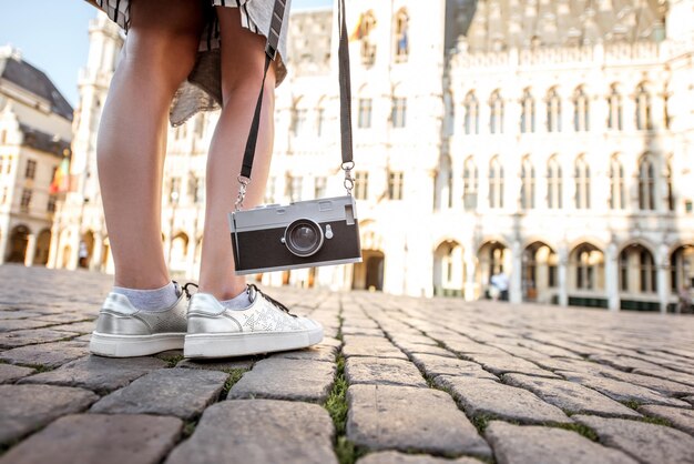 Kobieta stojąca z aparatem fotograficznym na Grand Place z ratuszem w tle na starym mieście w Brukseli, Belgia