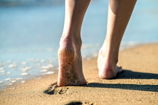 Kobieta Stopy Chodzenie Boso Po Piasku, Pozostawiając ślady Na Plaży.