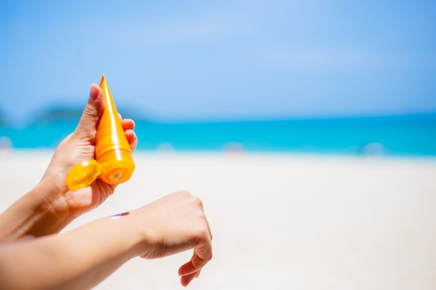 Kobieta stosuje sunscreen ochrony śmietankę przeciw turkusowemu morzu karaibskiemu