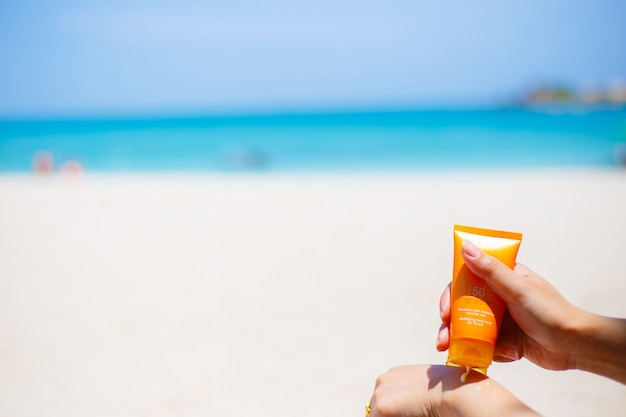 Kobieta stosuje sunscreen ochrony śmietankę przeciw turkusowemu morzu karaibskiemu