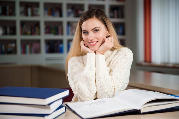 Kobieta Studentka Notatek Z Książki W Bibliotece. Młoda Kobieta Siedzi Przy Stole Robi Zadania W Bibliotece Uczelni.