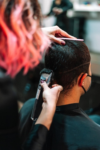 Kobieta stylizująca włosy klientów w salonie kosmetycznym za pomocą maszynki do strzyżenia