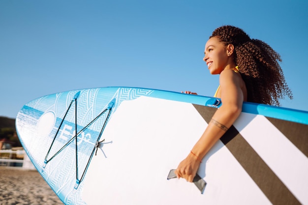 Kobieta surfer chodzi z deską na piaszczystej plaży Sport ekstremalny Podróż weekendowy styl życia