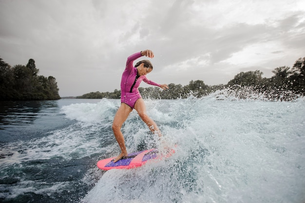 Kobieta surfingowiec jedzie w dół błękitną chełbotanie rzekę przeciw niebu