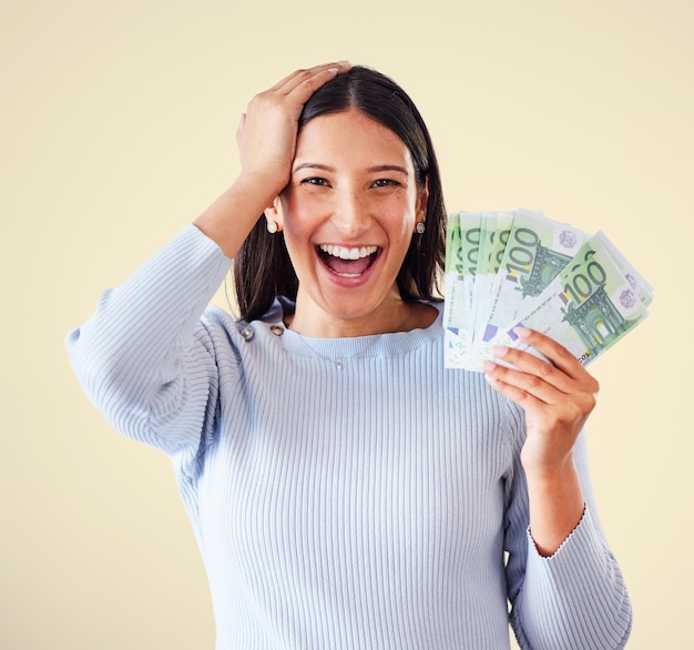 Kobieta świętuje sukces wygrywając pieniądze lub zwycięstwo na loterii, trzymając w ręku gotówkę lub banknoty Portret podekscytowany szczęśliwy i dumny zwycięzca krzyczy i śmieje się z żółtym tle copyspace