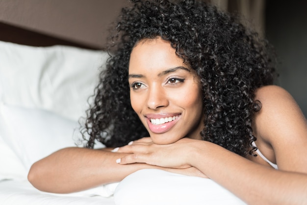 Kobieta szczęśliwa na łóżku ono uśmiecha się i rozciąga patrzejący kamerę w ranku